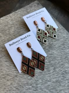 two pairs of beaded earrings sitting on top of a table next to each other