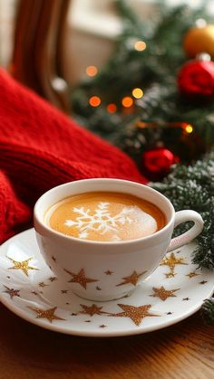 a cup of hot chocolate on a saucer next to a christmas tree with gold stars