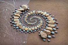 rocks arranged in the shape of a spiral on a sandy beach with water and sand