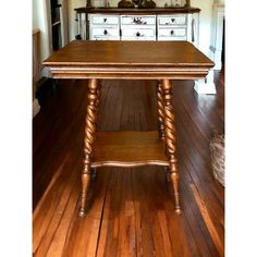 a wooden table sitting on top of a hard wood floor next to a white dresser