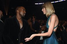 a woman in a blue dress talking to a man in a black suit and tie