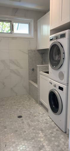 a washer and dryer in a small room with white cabinets on the walls