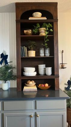 a wooden shelf filled with bowls and plates on top of a counter next to a potted plant