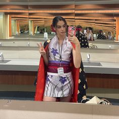 a woman taking a selfie with her cell phone in front of a mirror at an airport