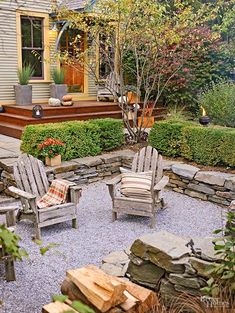 an outdoor patio area with chairs and fire pit surrounded by rocks, plants and trees