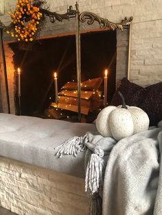 a white pumpkin sitting on top of a wooden bench next to a fireplace with candles