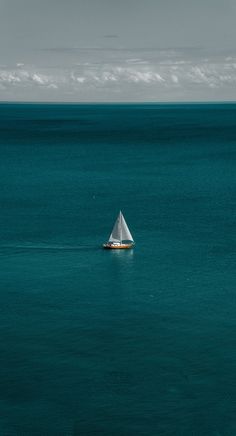 a small sailboat in the middle of an ocean