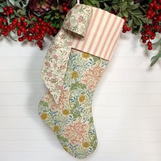 a christmas stocking hanging from a tree with berries and greenery around the stockings