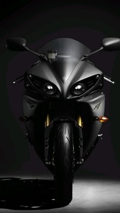 the front end of a black motorcycle with its lights on