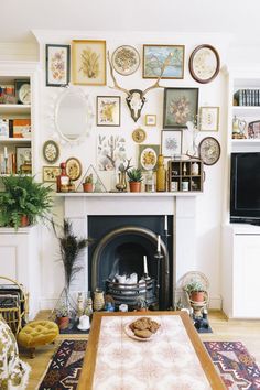 a living room with a fire place and lots of pictures on the wall above it