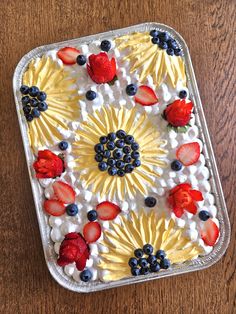 a cake with strawberries, blueberries and raspberries in it on a wooden table