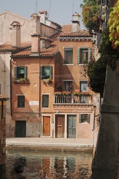 an old building with flowers on the balconies next to it's water way