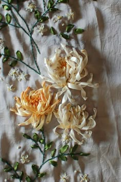 three white and yellow flowers are on a sheet