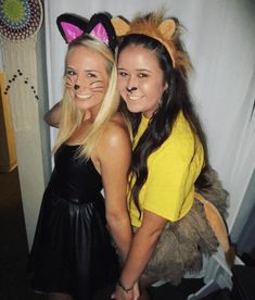 two girls dressed up in costumes posing for the camera with their faces painted like cats