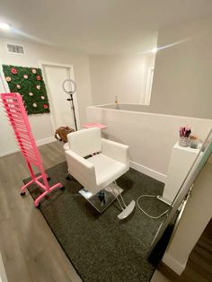 a white chair sitting on top of a hard wood floor next to a pink lamp