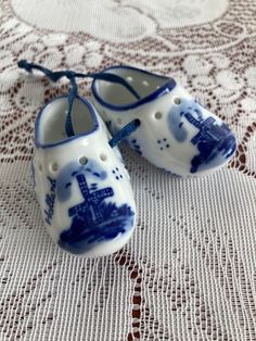 two blue and white baby shoes on a lace doily with the eiffel tower painted on them