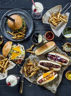 several different types of food are on the table, including hot dogs and french fries