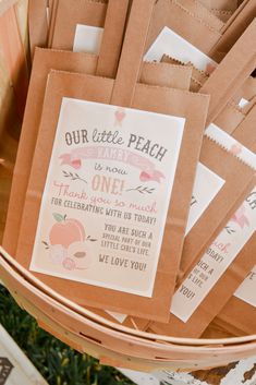 some brown paper bags sitting on top of a wooden basket filled with cards and envelopes