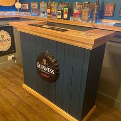 a wooden bar with guinness bottles on the back and behind it is a blue wall