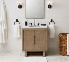 a bathroom vanity with a mirror above it and towels hanging on the wall next to it