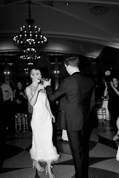 a bride and groom dancing at their wedding reception in black and white with chandelier