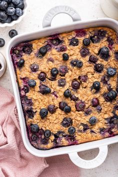 blueberry baked oatmeal in a white baking dish with fresh blueberries