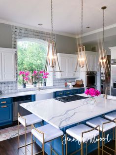 a kitchen with blue cabinets and white counter tops, gold accents and pendant lights hanging from the ceiling