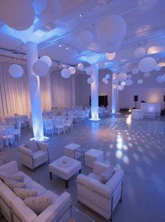 a large room with white couches and lights on the ceiling is lit by blue lighting