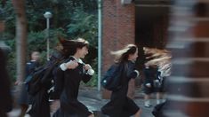 two girls in black dresses are running down the street with their hair blowing in the wind