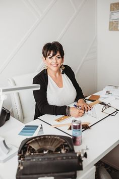 a woman sitting at a desk with a typewriter and pen in front of her