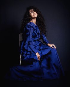 a woman in a blue dress sitting on a chair