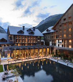 a large building that is next to a body of water in front of some mountains