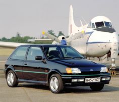 a black car parked in front of an airplane