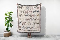 a woman standing in front of a white wall holding a blanket with dogs on it