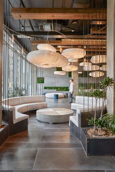 a large room with lots of white couches and potted plants on the floor