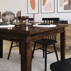 a dining room table with chairs and pictures on the wall in the backround