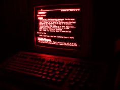 an old computer screen lit up in the dark with red light coming from behind it