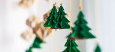 green paper christmas trees hanging from strings on a white wall with other decorations in the background