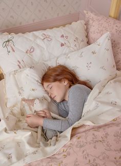 a woman laying in bed with her head on the pillow and holding a stuffed animal