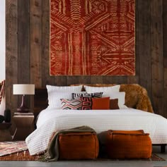 a bedroom with wood paneling and an orange tapestry on the wall above the bed