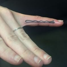 a person's hand with a small tattoo on the middle finger and an arrow in the middle