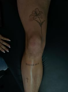 a man's leg with a cross and flower tattoo on his left calf area