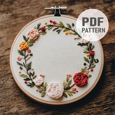 an embroidery pattern with flowers and leaves on it, in the middle of a hoop