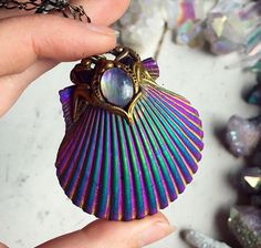 a hand holding a colorful shell shaped pendant