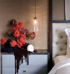 a white bed sitting next to a nightstand with flowers on it