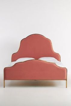 a pink bed with white pillows on top of it and an orange headboard in the middle