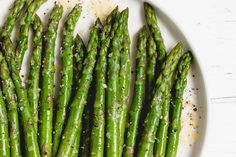 asparagus on a white plate with seasoning sprinkled over them and salt