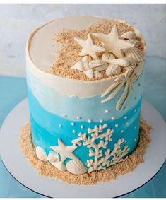 there is a blue and white cake with starfish on the top, and shells in the bottom