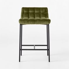 an upholstered bar stool with black legs and a green velvet seat cover on the back