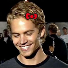 a smiling man with a red bow on his head and the word hello kitty in front of him